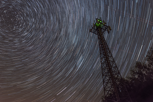 Radio tower near Reichenberg in the Bavarian forest at night with star trails around the Polarstern, Germany