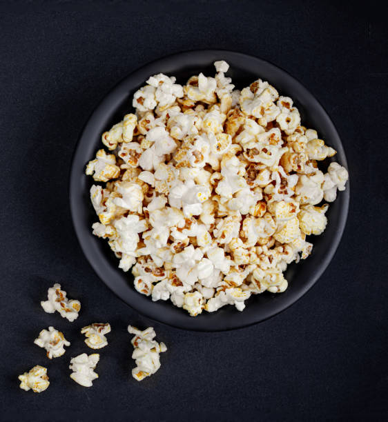 istock Scattered salted popcorn in a bowl  on black background with copy space. Homemade Popcorn  Top view. 