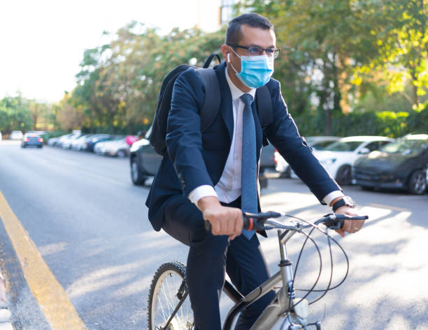 empresario en traje está en bicicleta para trabajar en bicicleta con escuchar música para evitar coronavirus - alternative energy audio fotografías e imágenes de stock