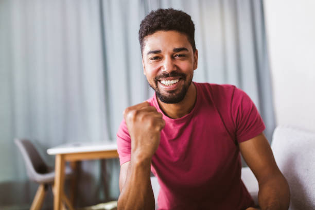 retrato do homem afro-americano sorridente, punhos de braço bombeado celebrando o sucesso. - pumped - fotografias e filmes do acervo