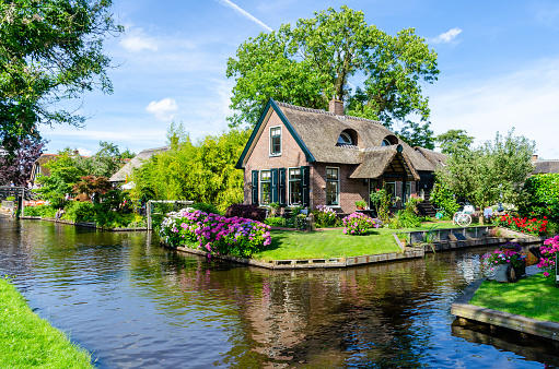Giethoorn, Netherlands: Landscape view of famous Giethoorn village with canals and rustic thatched roof houses. The beautiful houses and gardening city is know as \