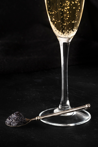 Black caviar and champagne on a black background with copy space, a still life