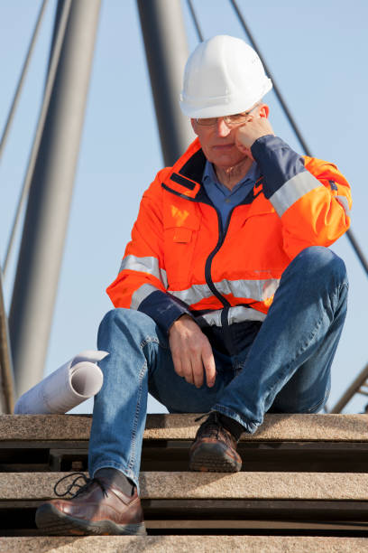 istock Sad or depressed engineer or foreman with protective workwear sitting in front of an industrial construction 1278921556