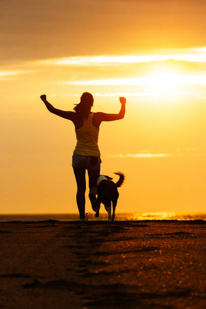 istock Woman and dog running on beach 1278923982