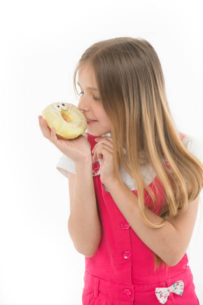 Child look at donut isolated on white. Little girl with glazed ring doughnut. Kid with junk food. Unhealthy eating and snack food.