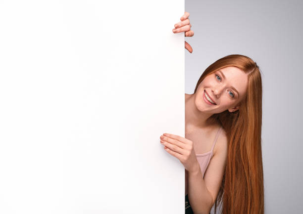 istock Cheerful ginger woman peeking out from empty placard 1278927828