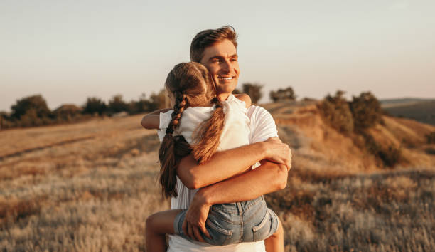 istock Happy father hugging daughter in field 1278927861