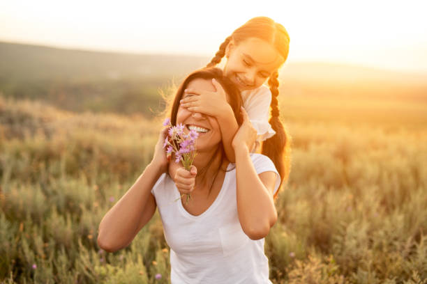 Daughter playing with mother during sunset