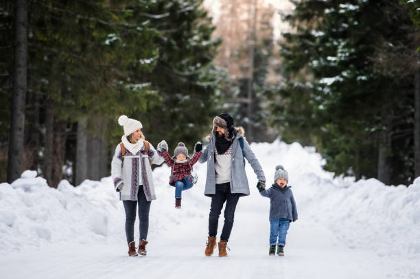 padre e madre con due bambini piccoli nella natura invernale, camminando nella neve. - garment snow little boys child foto e immagini stock