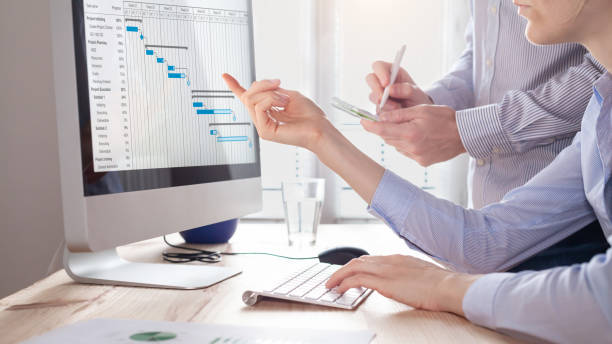 istock Project management team updating planning schedule with Gantt chart on computer at the office to communicate on task progress and plan the next deliverables. Program manager and assistant discussing 1278931804