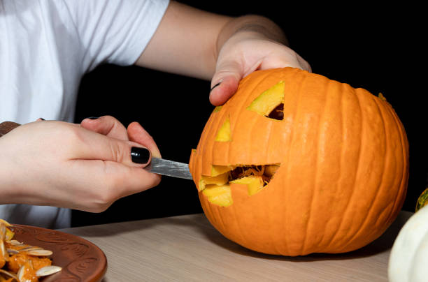 istock Cutting out faces from a fresh pumpkin. Preparing for the Halloween celebration. 1278937056