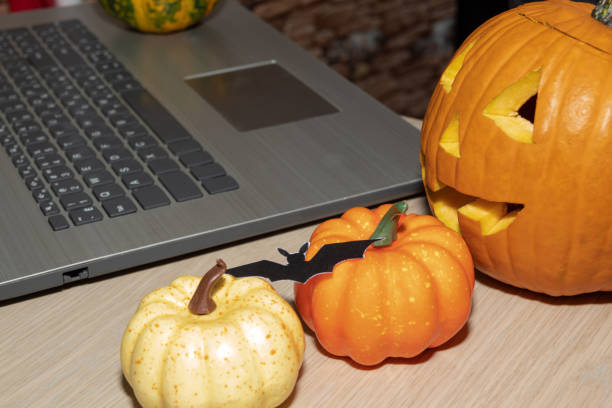 Lantern made of pumpkins, small pumpkins are near the laptop. A freelancer's workplace during Halloween. stock photo