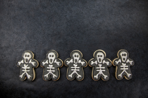 Skeleton cookie photography with dark black background and copy space. Perfectly usable for all spooky Halloween projects.