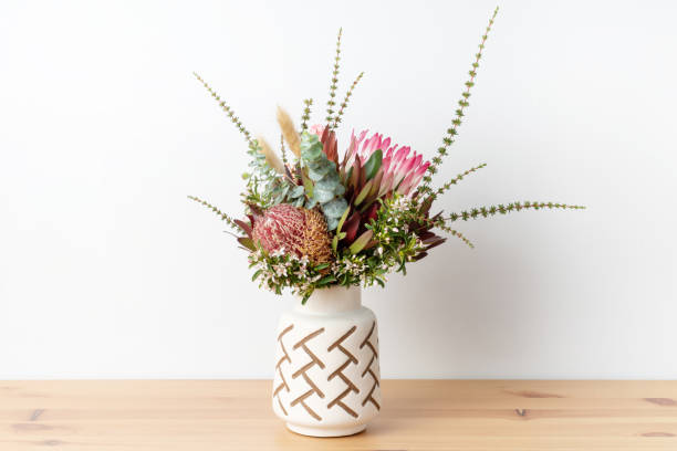 australische inheemse bloem regeling van banksias, protea en eucalyptus bladeren, in een patroonvaas. - pronkstuk stockfoto's en -beelden