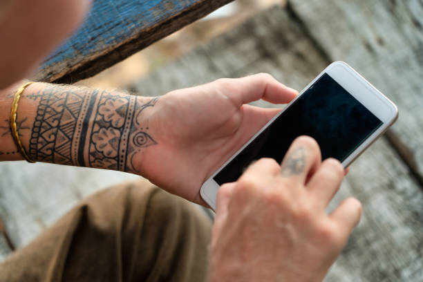 istock Tattoo female hands using smart phone over the shoulder pov 1278938718