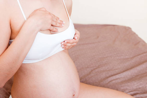 close up des femmes enceintes ayant des sentiments douloureux dans le sein. femme vérifiant son sein pour le cancer - abdomen women massaging human hand photos et images de collection