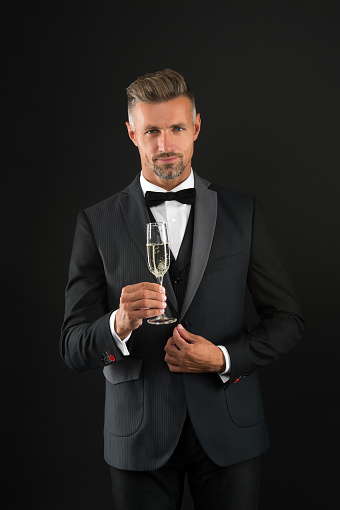 Handsome man tuxedo suit drink champagne black background, celebrate anniversary concept.