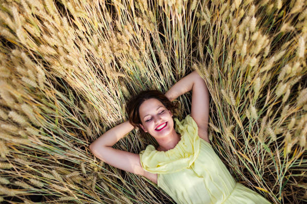 One young woman enjoying nature in a wheat field on a summer evening at sunset.