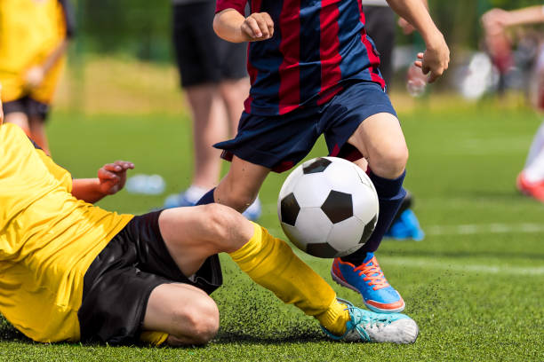 School boys playing football game. Young players kicking soccer ball on sports grass pitch. Happy children compete on a field School boys playing football game. Young players kicking soccer ball on sports grass pitch. Happy children compete on a field football league stock pictures, royalty-free photos & images