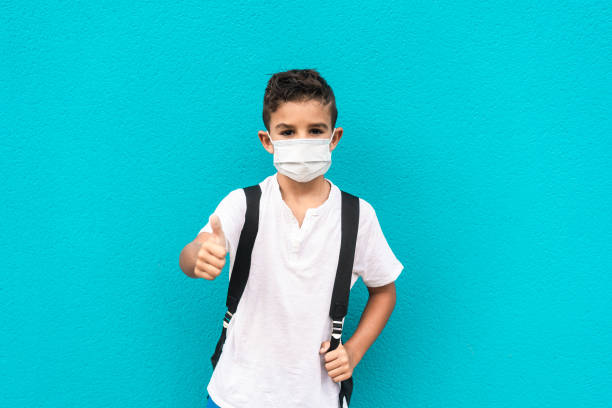 istock Little kid with face mask going back to school with thumbs up during coronavirus outbreak - Focus on boy's face 1278951679
