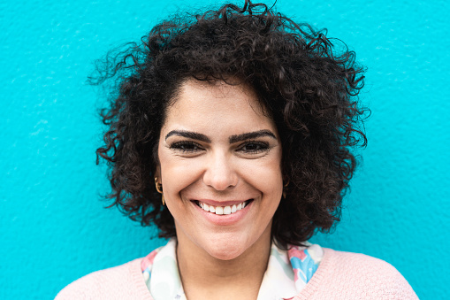 Portrait of cheerful woman smiling in front of camera with blue background - Focus on lady's eyes