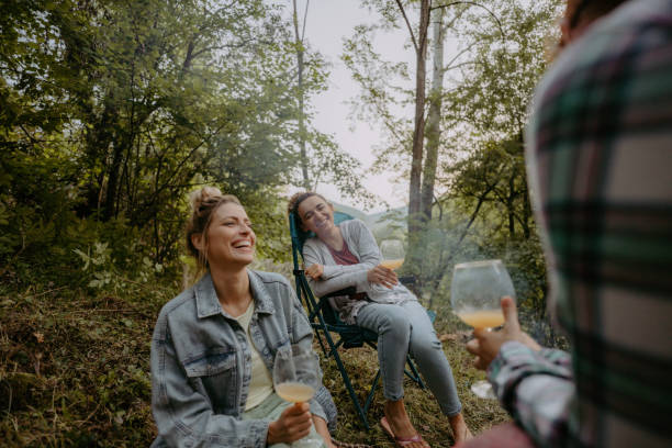 istock Young women sitting by campfire and sipping wine 1278953391