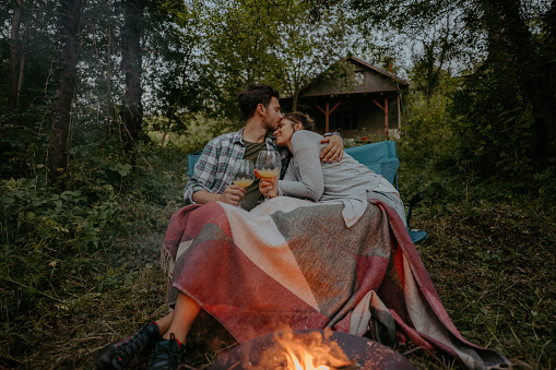 Photo of a couple who enjoy camping, having a romantic date by the river, deep in the forest.