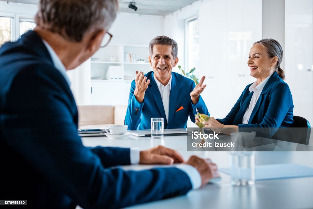 Senior business people in the office Senior businesswoman and businessmen wearing elegant suits sitting at the table in the office and discussing. Meeting Stock Photo