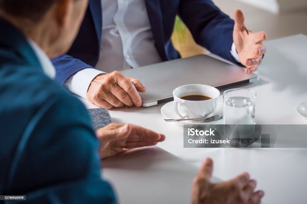 Senior businessmen during meeting Senior entrepreneur wearing elegant suits sitting at the table in the office and discussing. Close up on hands, unrecognizable person. Business Stock Photo Senior businessmen during meeting Senior entrepreneur wearing elegant suits sitting at the table in the office and discussing. Close up on hands, unrecognizable person. Business Stock Photo