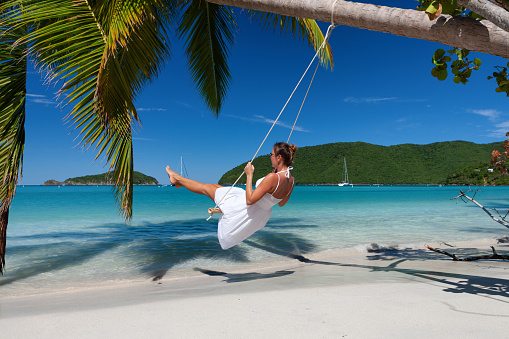 attractive woman on a swing at a tropical beach in the Caribbean, Maho Bay, St. John