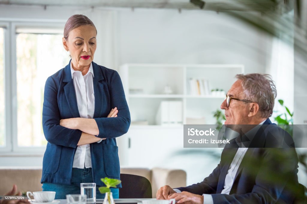 Shareholders during business meeting Worried senior businesswoman talking with his shareholder about problems. They are in the modern office. 65-69 Years Stock Photo