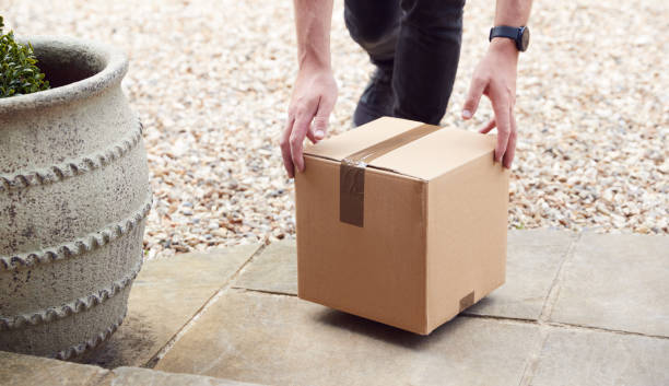 Close Up Of Delivery Driver Putting Package On Doorstep Outside House Close Up Of Delivery Driver Putting Package On Doorstep Outside House doorstep stock pictures, royalty-free photos & images