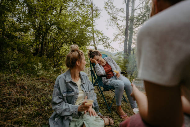 istock Young women sitting by campfire and sipping wine 1278958424
