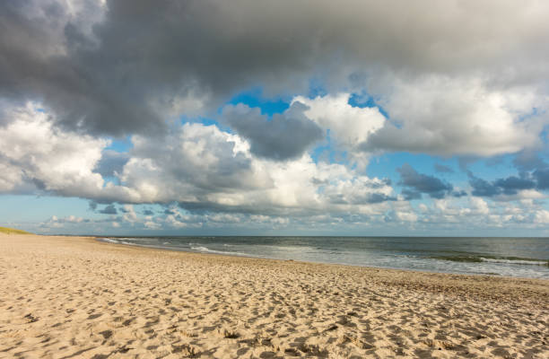 istock Beach sand with blue sky and dramatic clouds at coastline waterfront in soft evening sunset light. Hvidbjerg Strand, Blavand, North Sea, Denmark. 1278958769