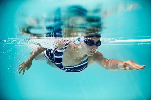Teenage girl practicing swimming crawl in the pool. Nikon D850
