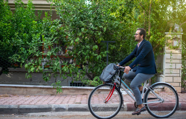 Alternative commute concept. Young man going to work with his bike. Alternative commute concept. Young man going to work with his bike. Young man not using public transport goes to work by bicycle leather medical bag stock pictures, royalty-free photos & images