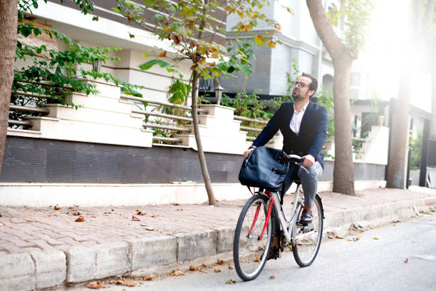 Alternative commute concept. Young man going to work with his bike. Alternative commute concept. Young man going to work with his bike. Young man not using public transport goes to work by bicycle leather medical bag stock pictures, royalty-free photos & images