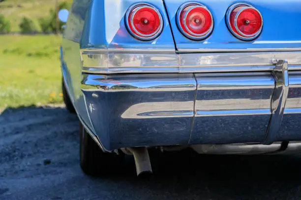 Photo of Blue classic car from behind with red rear lights.