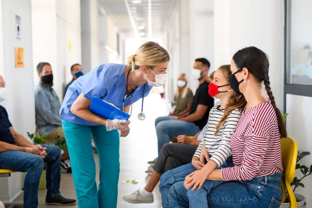 Portrait of nurse and patients with face masks, coronavirus, covid-19 and vaccination concept. Portrait of nurse with face mask talking to patients, coronavirus, covid-19 and vaccination concept, in waiting room. waiting room stock pictures, royalty-free photos & images