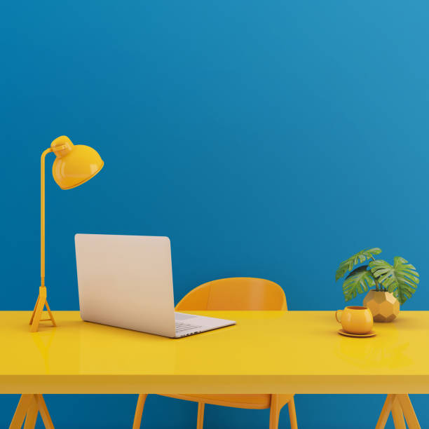 istock Table with laptop mock up.Yellow chair,lamp,table on blue background.Working space concept3d rendering 1278971840