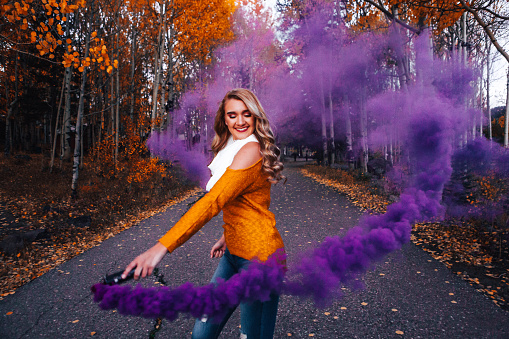 Artistic, Spooky, Dark, Colorful Portrait of a Teenage or Young Adult Caucasian Female Using a Purple Smoke Bomb in the Autumn Fall Colors Outdoors in the Grand Mesa National Forest near Grand Junction, Colorado