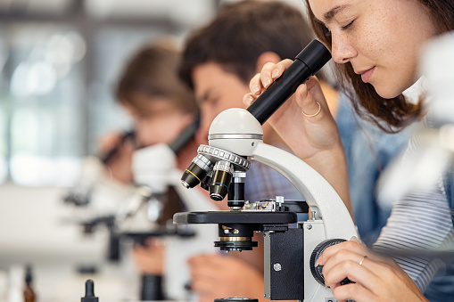 Medical science, woman and microscope in a laboratory for research, analytics and to study particle. Scientist person with glasses for dna or bacteria in lab for innovation, future and biotechnology