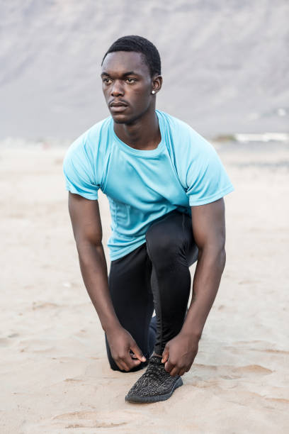 istock Black sportsman tying shoelaces on beach 1278973986