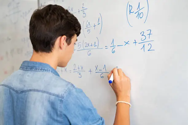 Photo of College student solving math equation on white board