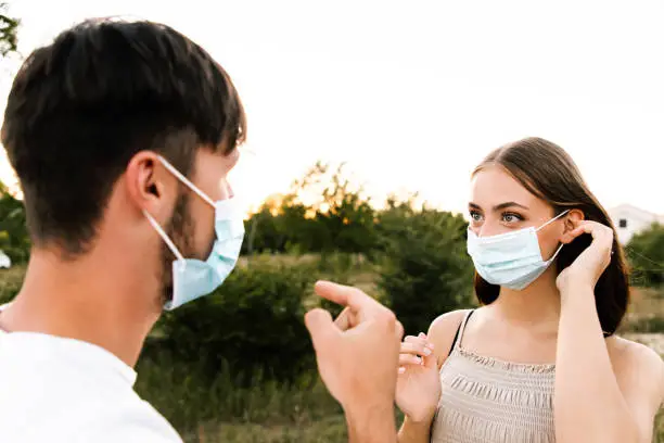 Photo of Young man reminding his girlfriend to wear corona virus protective face mask