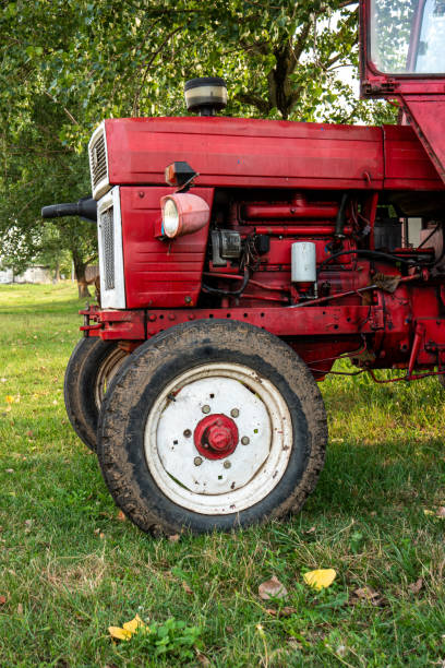 istock Old small red agriculture tractor parked on the grass summertime before sunset three-quarter view 1278976569