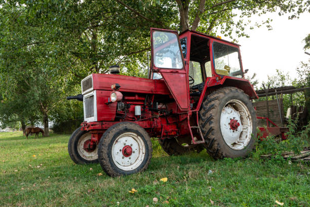 istock Old small red agriculture tractor parked on the grass summertime before sunset three-quarter view 1278976571