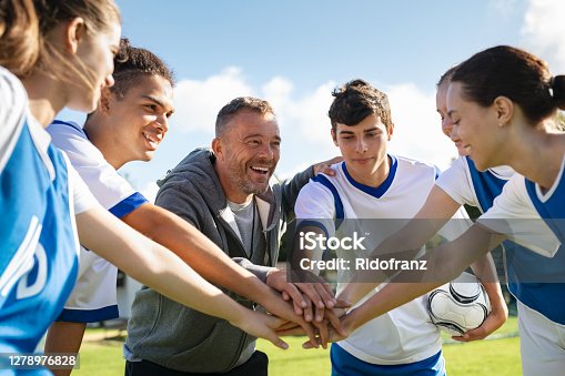 istock Team of young football players stacking hands before match 1278976828