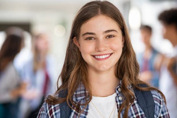 Happy student girl at high school Portrait of beautiful girl standing in college campus and looking at camera. University young woman with backpack smiling. Satisfied and proud student girl standing in high school hallway. 16 17 years stock pictures, royalty-free photos & images