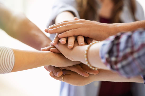 Young multiethnic friends stacking hands Young people putting their hands together. Close up of girls and guys stacking hands together. Friends with pile of hands showing unity and teamwork: collaboration and support concept. stacked hands photos stock pictures, royalty-free photos & images